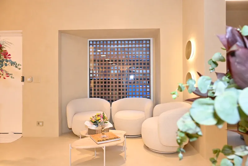 Recepção do Studio AMI com poltronas brancas, flores e cobogó