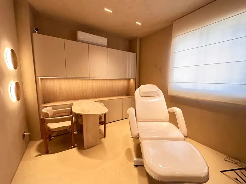Sala de estética com maca, armários de madeira e luz suave